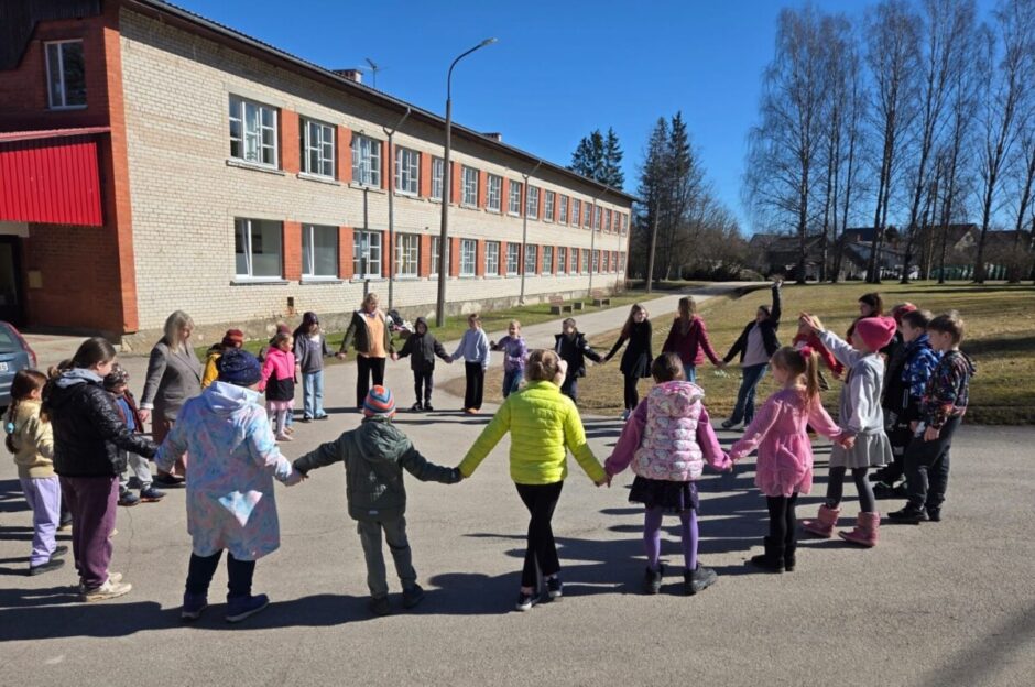 Skolēni un skolotāji sadevušies rokās aplī pie Ķeipenes pamatskolas