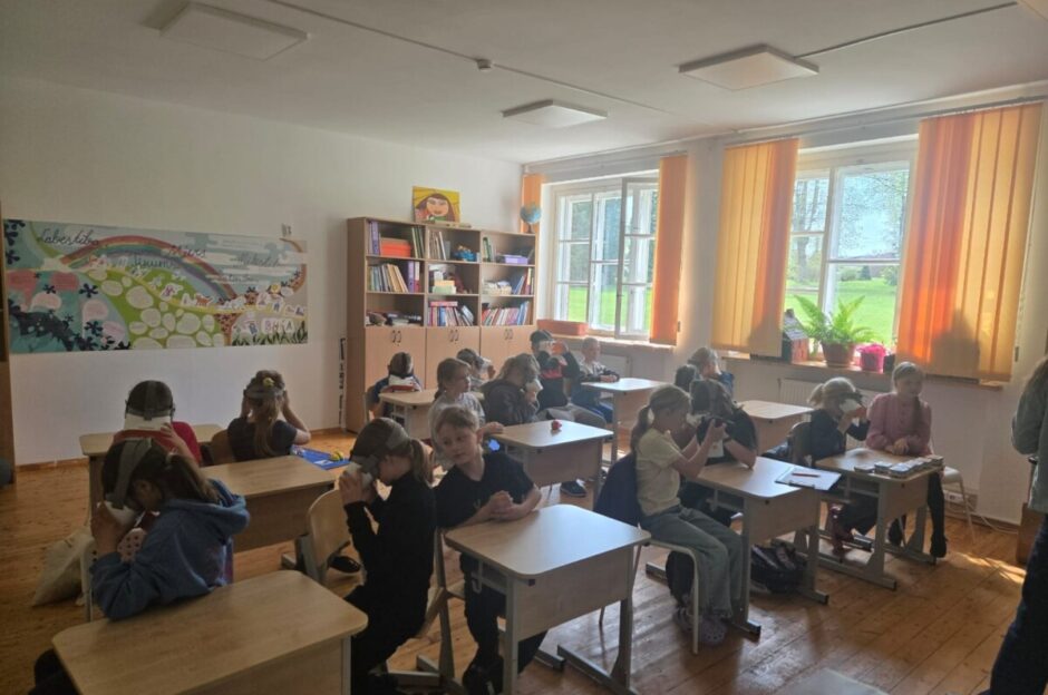 Skolēni klasē; uz sienas skolēnu gleznojums