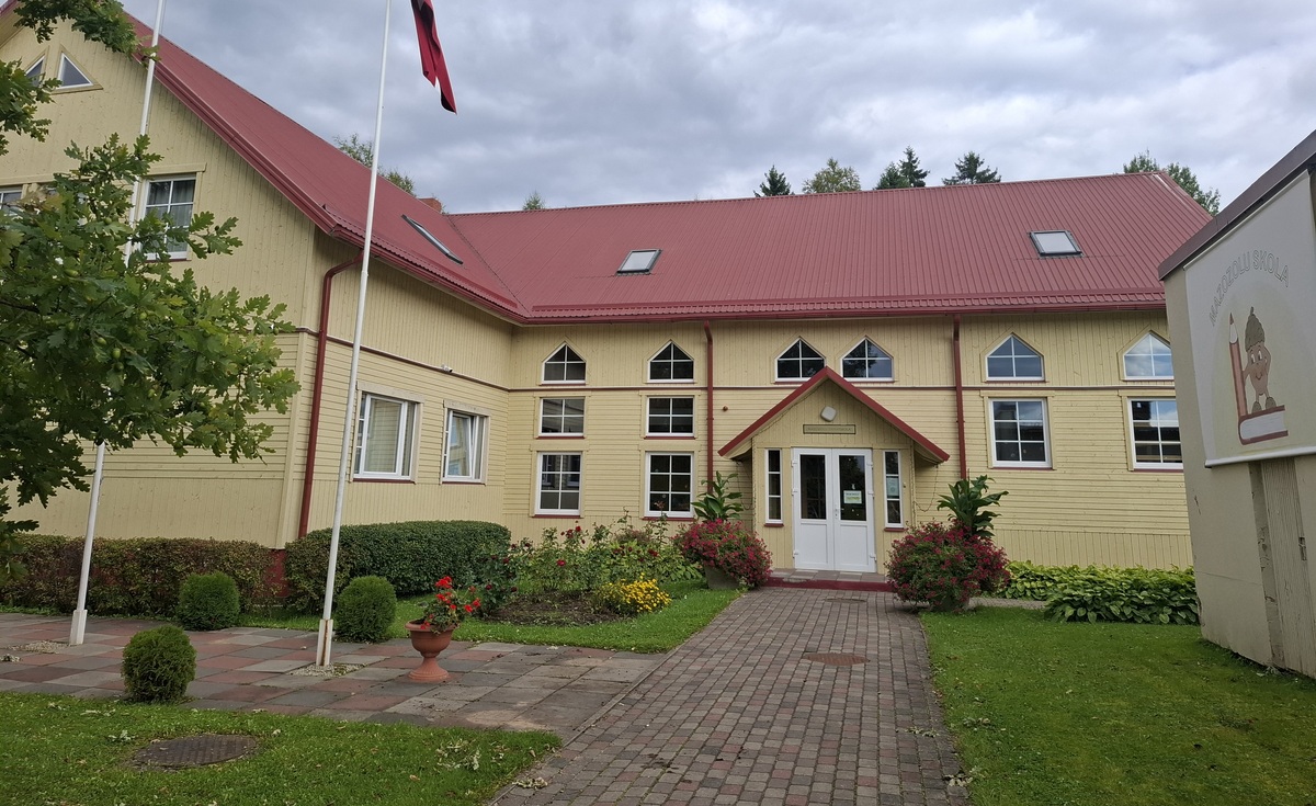 Mazozolu skolas ēka ar Latvijas karogu un ziediem pie ieejas