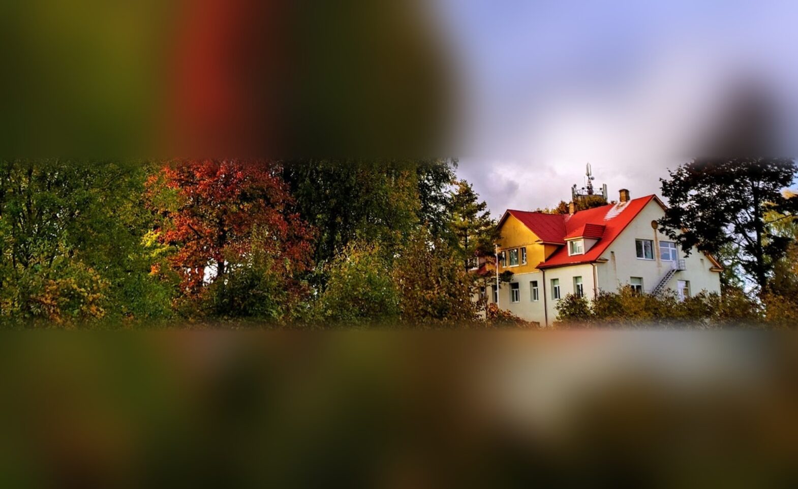 Meņģeles skolas ēka ar sarkano jumtu un sarkanlapu kļava rudenī