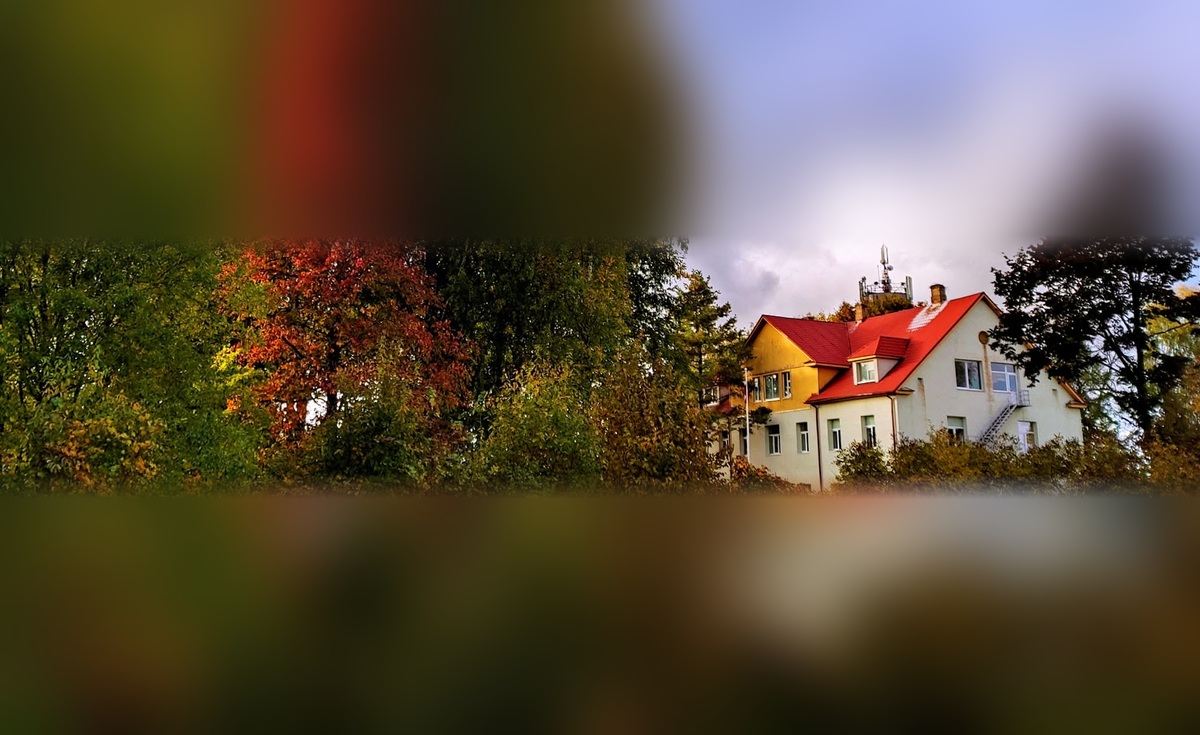 Meņģeles skolas ēka ar sarkano jumtu un sarkanlapu kļava rudenī