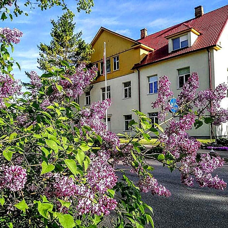 Meņģeles skolas ēka ar ziedošiem ceriņiem