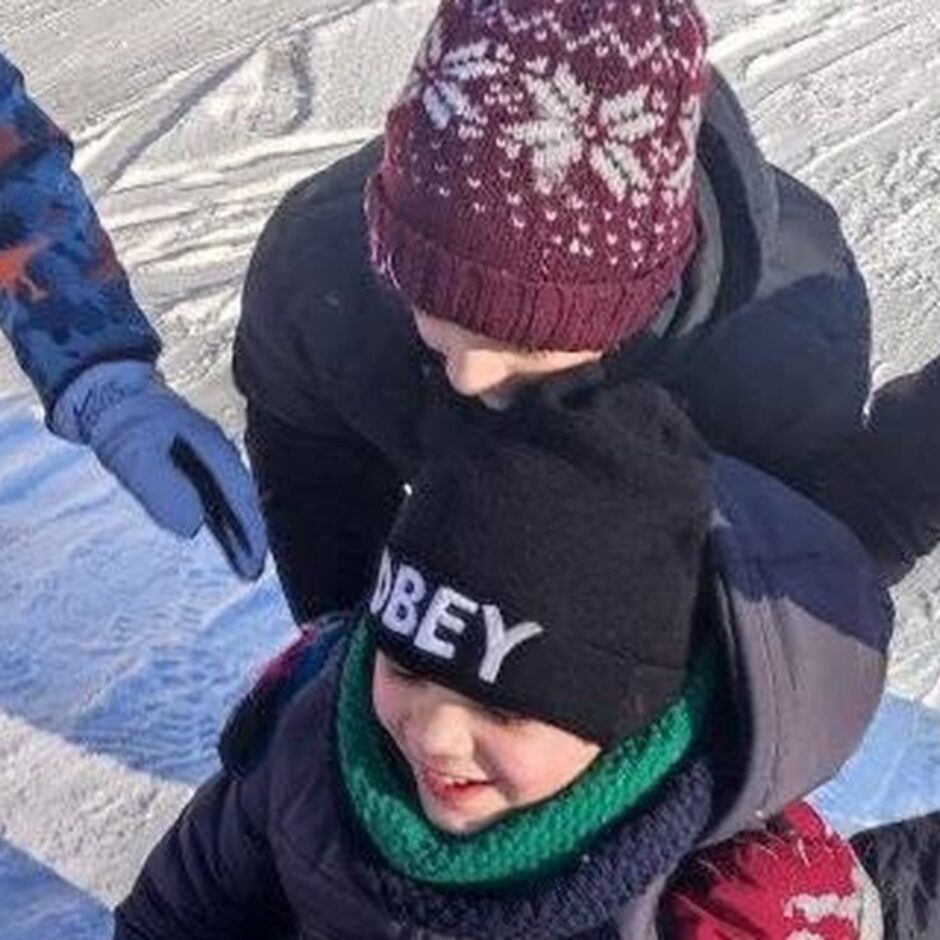 Skolēni brauc ar ragavām saulainā ziemas dienā