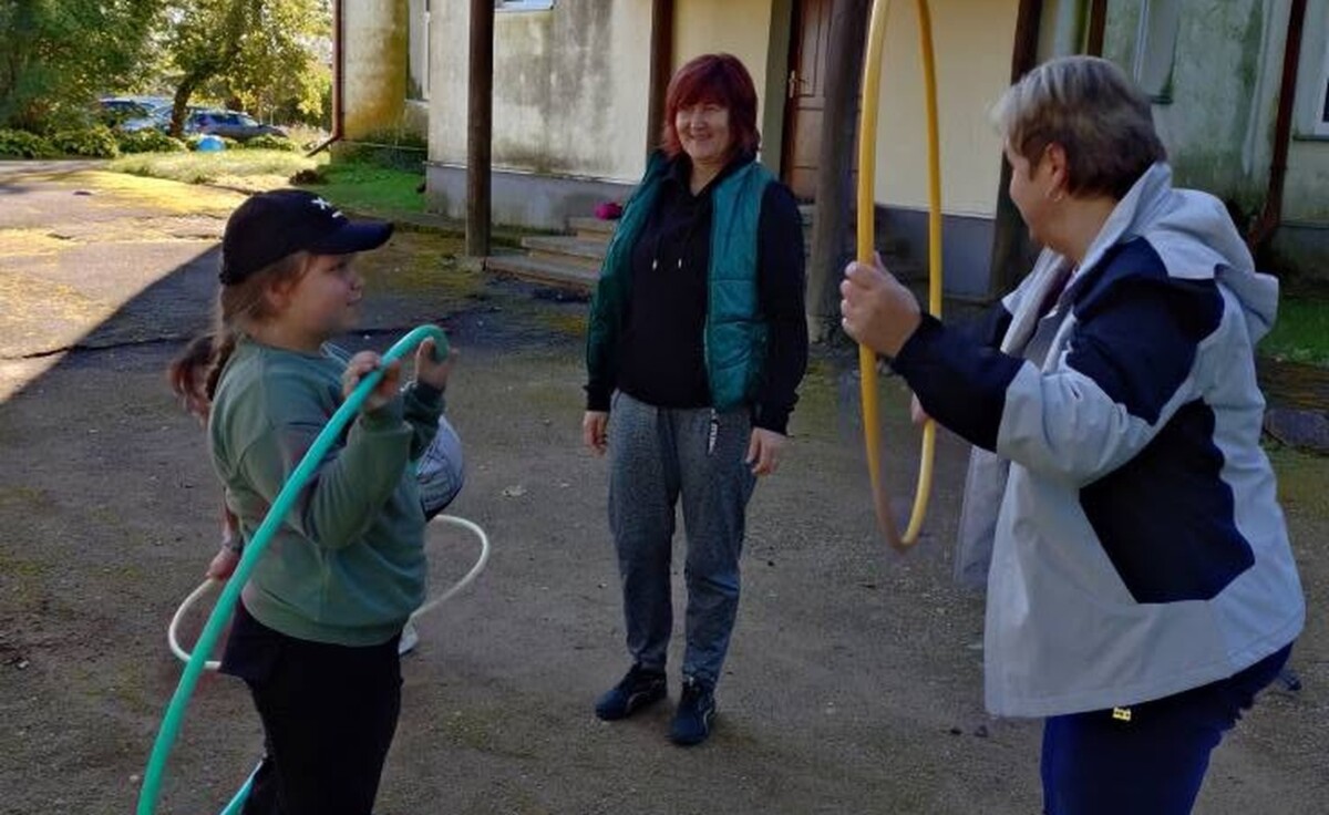 Skolniece ar stīpām sporto kopā ar pieaugušajiem pie skolas